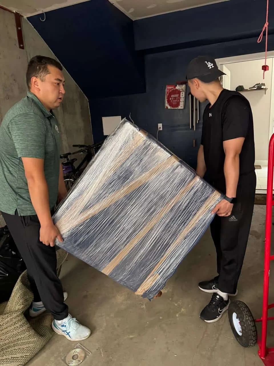 Two movers carrying a wrapped piece of furniture